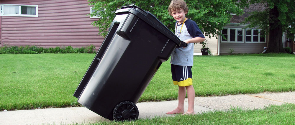 Sgt. Poopers can disinfect garbage carts and recycling carts Image of a boy moving a garbage cart